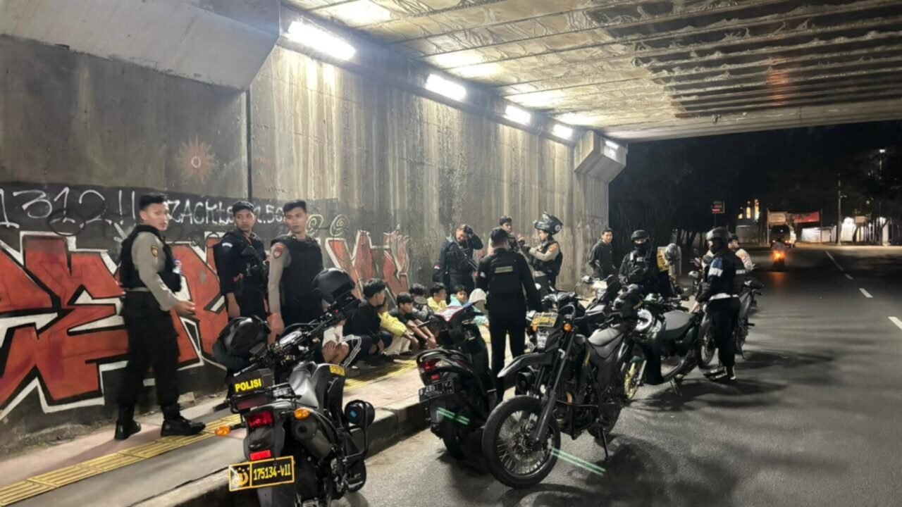 Personel Brimob Polda Metro Jaya memeriksa pengendara saat patroli malam di kawasan Terowongan McD, Cipayung, Jakarta Timur.
